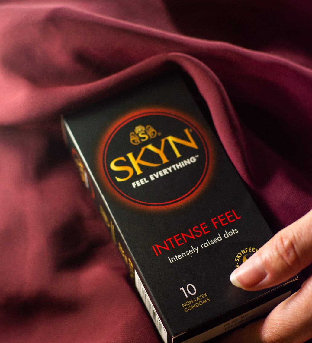 Hand reaching SKYN Intense Feel condom box