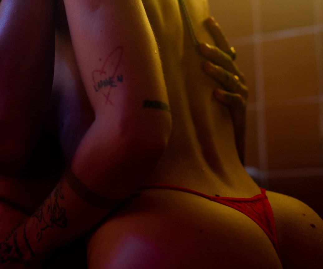 Back of a tattooed girl kissing with red thong kissing